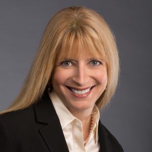 headshot of woman with black blazer, white collared shirt, smiling