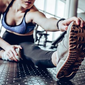 woman sitting in gym near window while make stretching exercises