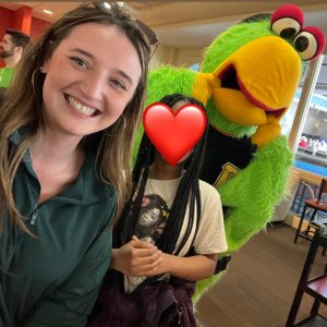 girl with green hoodie taking selfie with girl and parrot mascot