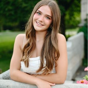 woman with long brown hair and white dress smiling