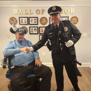two men shake hands by wall of honor in senior home