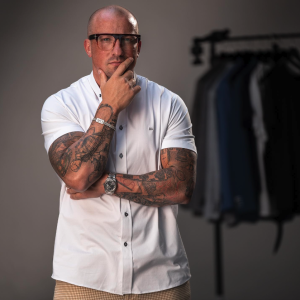 man with tattoos and glasses poses