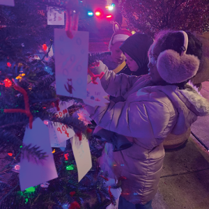 kids putting written cards on tree at night