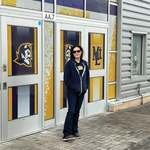 woman with sunglasses stands outside of MTLHS athletics complex