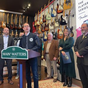 people behind podium with guitars in background