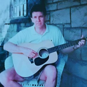 man playing guitar on porch