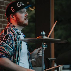 man playing drums with baseball hat