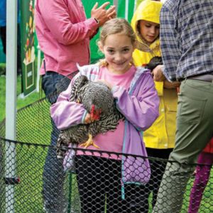 girl holding chicken in purple jacket