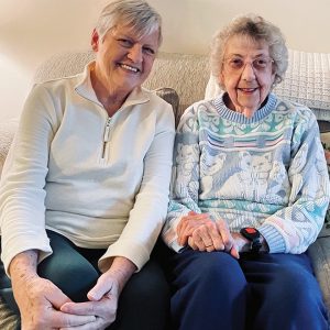 two older women on couch smile