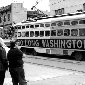 A black and white photo of a trolly that says "So long washington Rd" and people watching it go by.