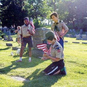 three boys put american flags on graves