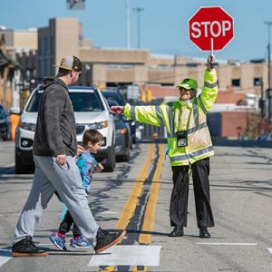 crossing guard helps man and child cross street