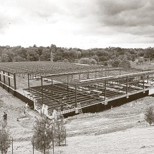 black and white photo of a structure being built with trees in background