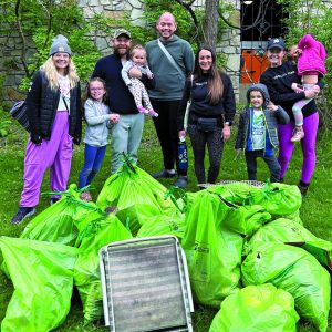 group of adults and children with bags of garbage from an Earth Day cleanup