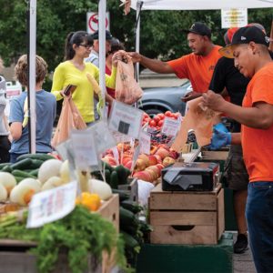 shoppers and vendors at farmers market with produce