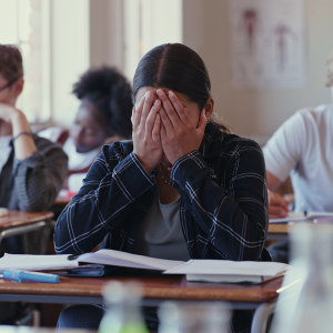 student at desk with head in hands