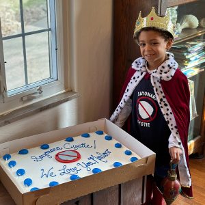 boy wearing crown and cap smiling with shirt that says sayonara cystie