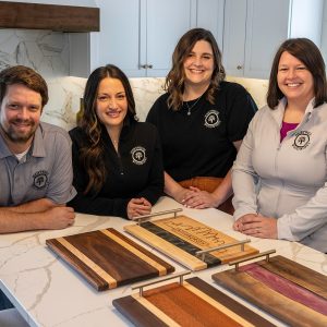 a man and three women standing next to a counter with cutting boards sitting on it