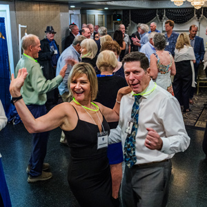 a man and woman dressed up dancing in a crowd holding drinks