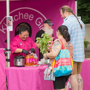 people buying from Kimchee girl pink stand at farmers market