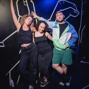Two women and a man leaning up against a wall posing for the picture