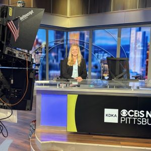 woman in business attire behind CBS Pittsburgh newsdesk with camera