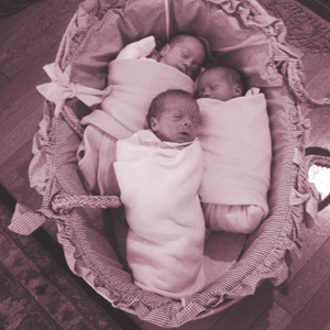 three babies swaddled in a bassinet