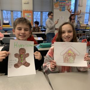 boy and girl at school, smiling holding hand-drawn holiday cards