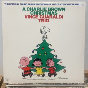 A Charlie Brown Christmas vinyl record cover. Three children Peanuts characters and snoopy around a tree