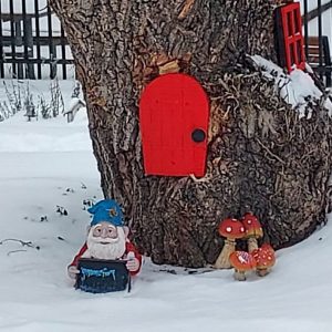 a gnome, mushrooms and door by a tree with snow