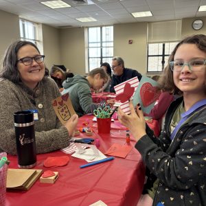 mom and daughter with short hair and glasses holding Valentine cards