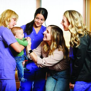 four women, one holding a baby, all smiling in a hospital