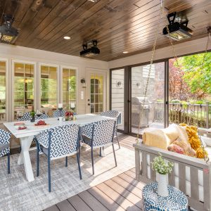 enclosed deck with chairs and tables and large windows