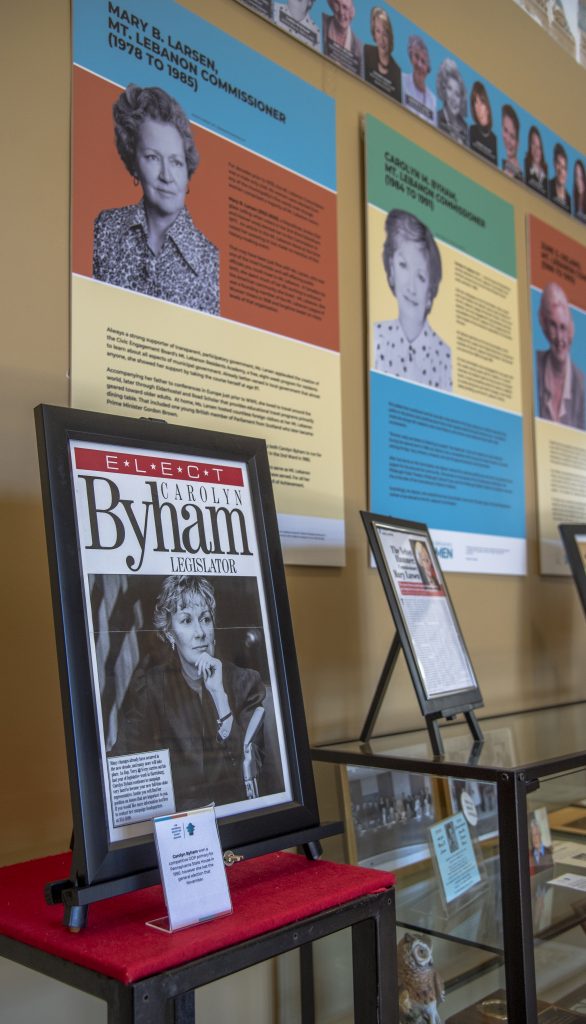 colorful posters and framed articles in a glass case in a museum