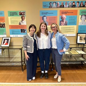three women smile for photo in a museum exhibit