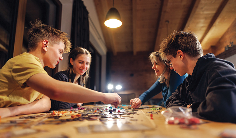 4 teens sitting around a table playing tabletop games