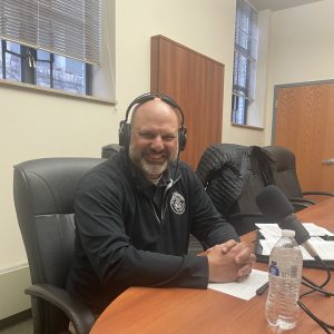 Mt. Lebanon Police Chief, Jason Haberman sits at a table with headphones.