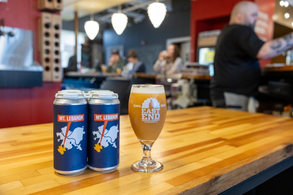 beer cans and a pint of beer on a table in a restaurant