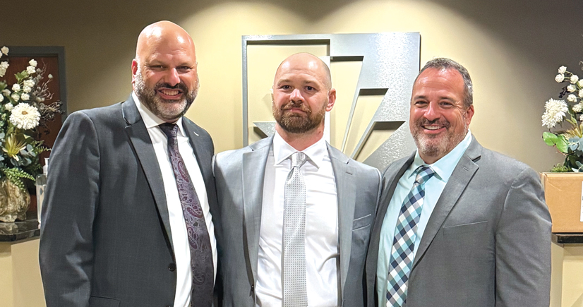 three men in suits smiling and ties standing in the municipality lobby