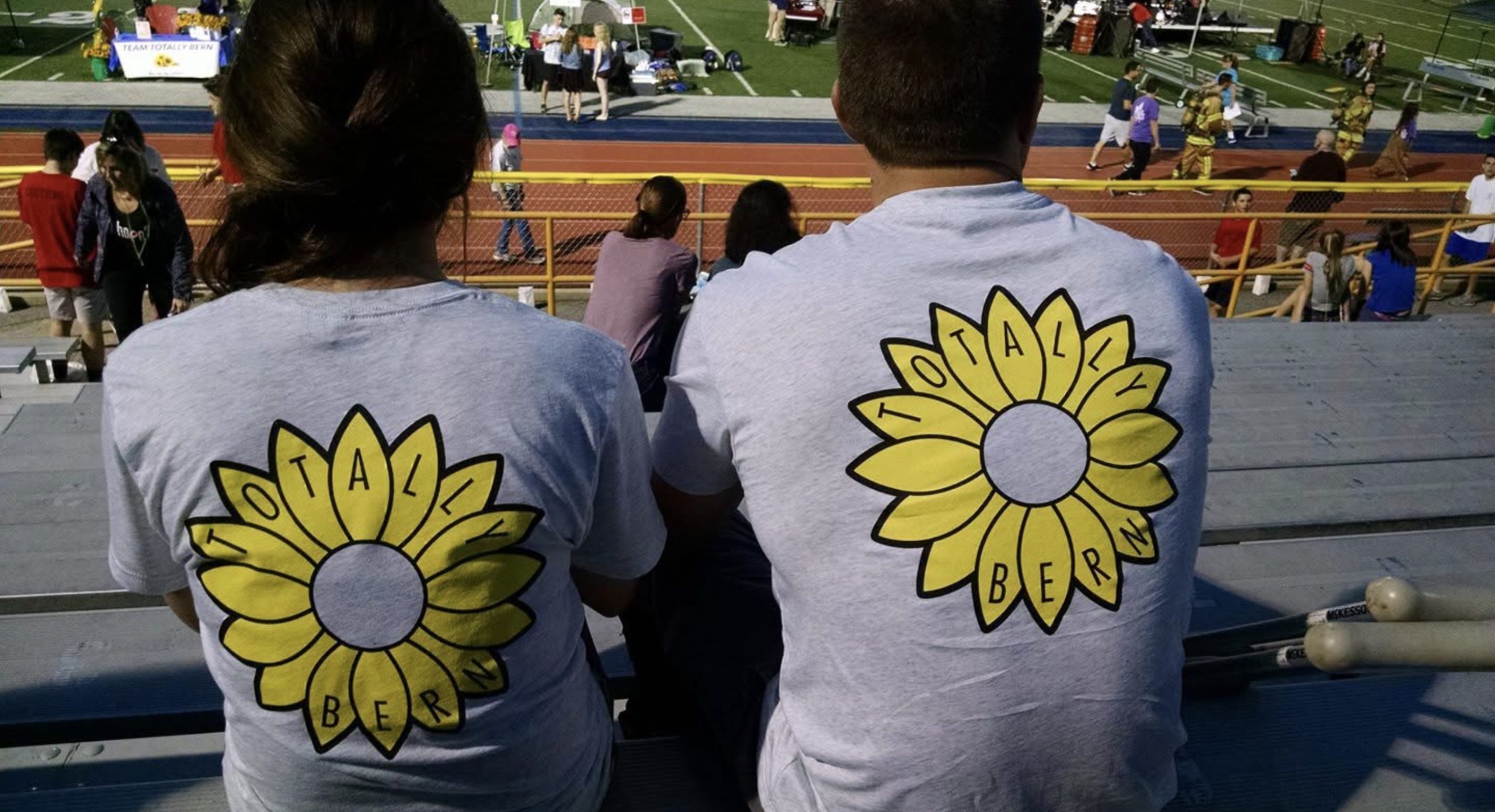 two people sitting in bleachers with matching t shirts with sunflowers
