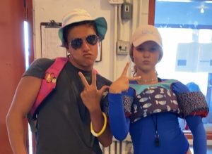 two teens in swim gear and hats pose for photo with peace signs
