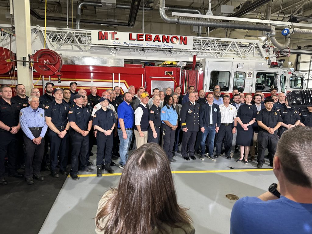 A large group of firefighters in front of a fire truck