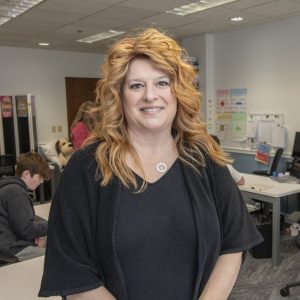 woman with black shirt and long blonde hair smiling in a learning center