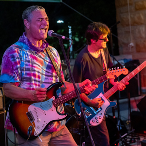two men playing guitar and singing at a concert