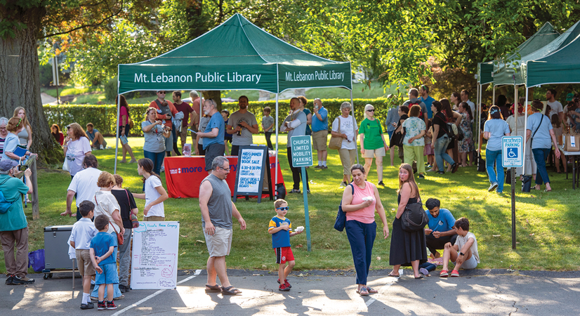 people outside at a festival with library tents in the background
