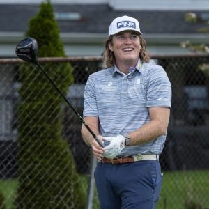 man in blue outfit and white hat swinging golf club outdoors