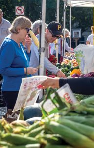 people shopping at an outdoor farmers market