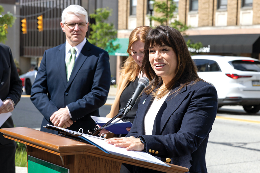 several people in business clothes stand at podium in a city outdoors