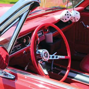 a closeup of the dashboard and steering wheel on a red mustang convertable