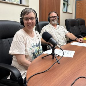 Eric Milliron, Mt. Lebanon’s economic development and commercial districts manager, and WYEP program director Liz Felix pose with headphones on in front of microphones.